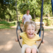 Screaming boy on swing with Dad in back