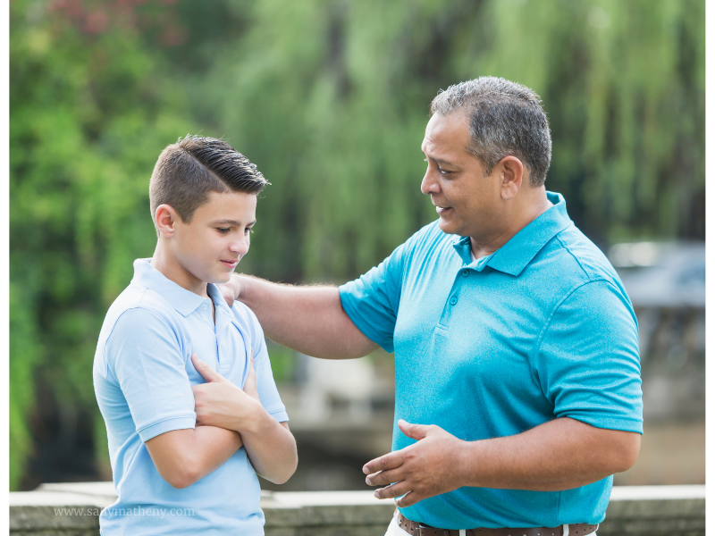 Dad with hand on son's shoulder and talking with him.