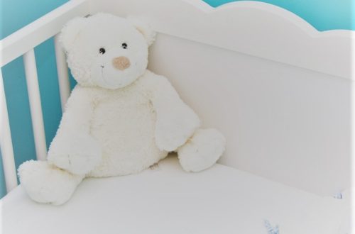 white teddy bear in crib