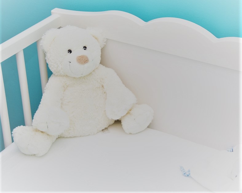 white teddy bear in crib