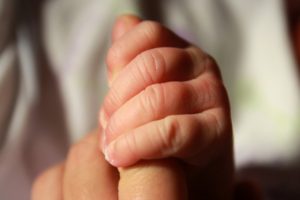 baby clasping adult finger