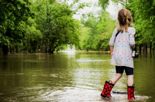 Little girl in raiboots standing in floodwaters