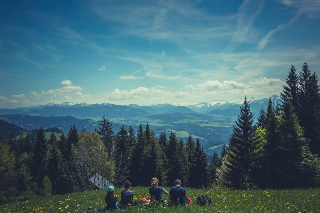 Family sitting together facing the mountains, sharing about the Creator of their joy.