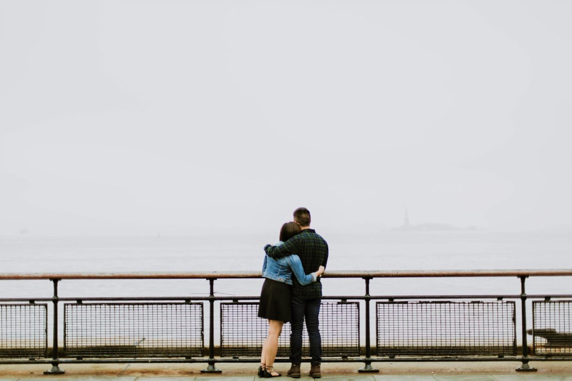 couple on bridge facing fog