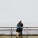 couple on bridge facing fog