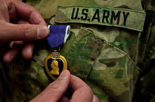 Hand pinning Purple Heart onto Army uniform. Public domain photo.