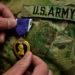 Hand pinning Purple Heart onto Army uniform. Public domain photo.