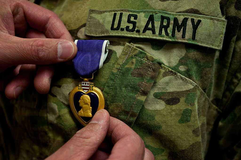 Hand pinning Purple Heart onto Army uniform. Public domain photo.