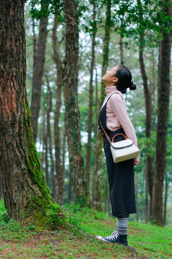 Young woman taking a deep breath in a forest. Planter of peace.