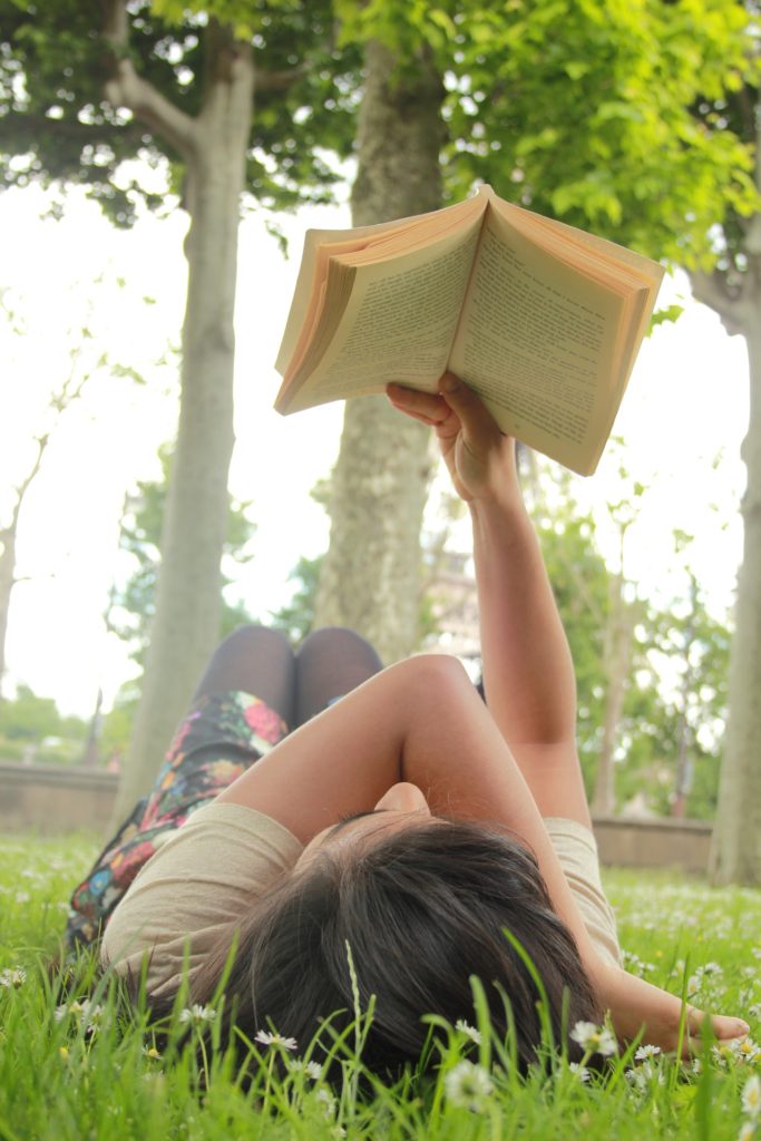 woman lying on grass alone reading