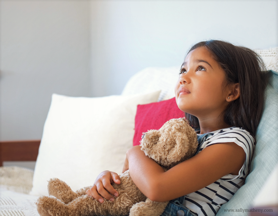 Little girl looking up and hugging teddy bear - Is Jesus real? (Canva photo)
www.sallymatheny.com