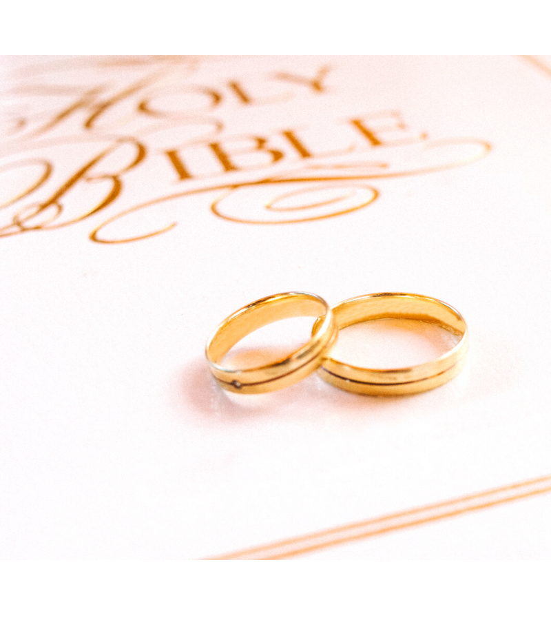 white Bible with gold wedding rings