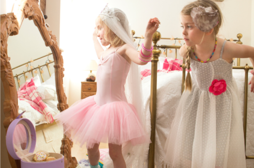 Two little girls playing in bride dress-up clothes.