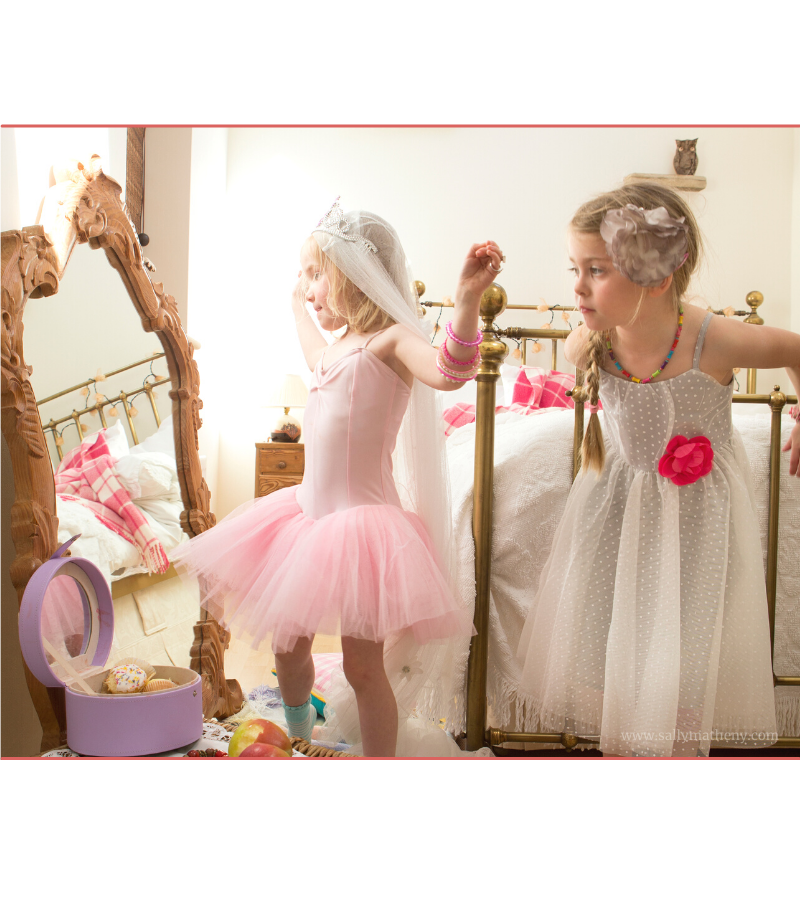 Two little girls playing in bride dress-up clothes.