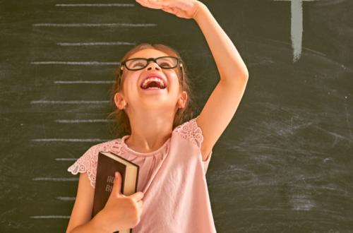 Girl in front of growth chart holding a Bible.