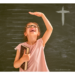 Girl in front of growth chart holding a Bible.