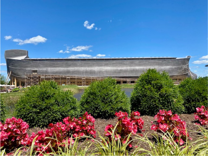 Sally Matheny's photo of the Ark Encounter. Shows huge wooden structure with hot pink flowers and green shrubs in the forefront. 2021.