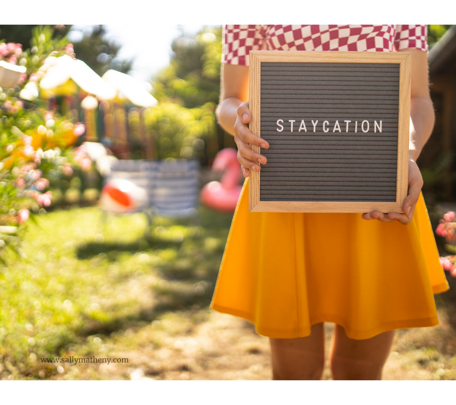 Shows a woman holding a sign that says "Staycation."