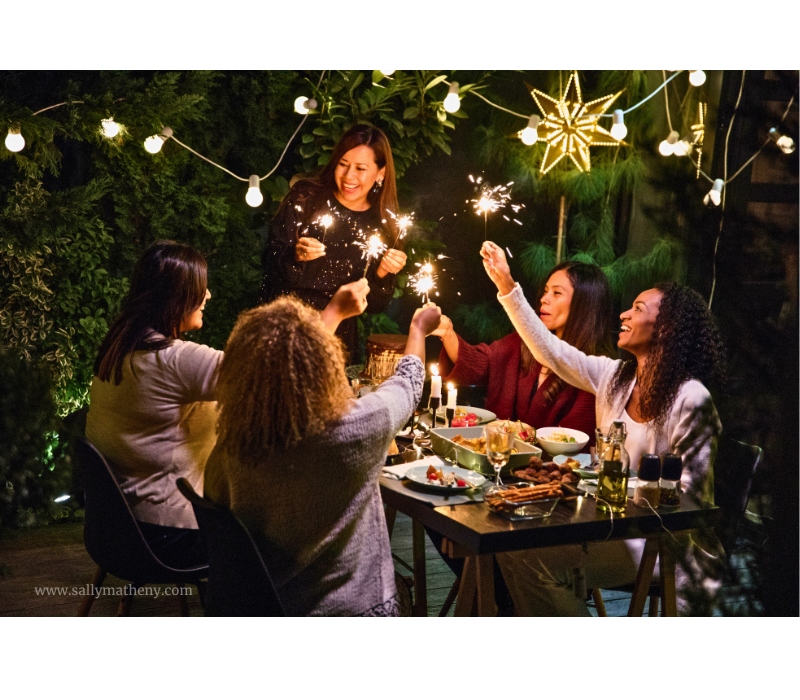Shows an outdoor dinner party with people holding sparklers.