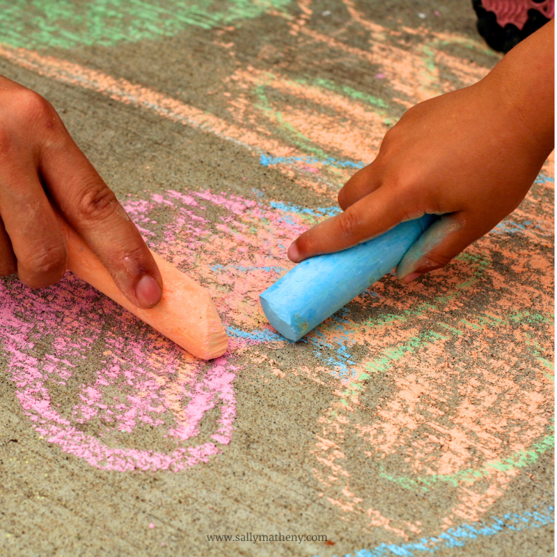 Little children coloring with sidewalk chalk.